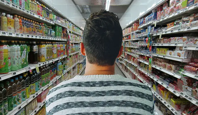 man looking down grocery store aisle